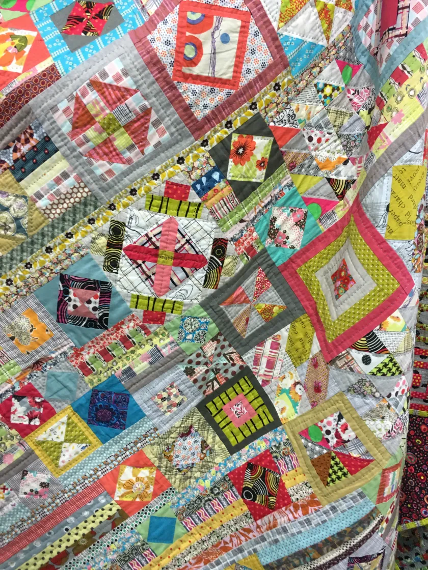 Detailed view of an intricately pieced patchwork quilt featuring many small geometric and floral fabric blocks in bright colors